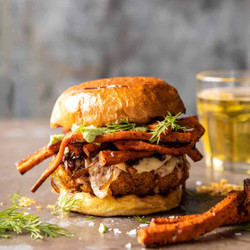Crispy Quinoa Burgers Topped With Sweet Potato Fries And Beer Caramelized Onions