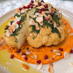 Whole roasted cauliflower on romesco with herby topping and flaked almonds